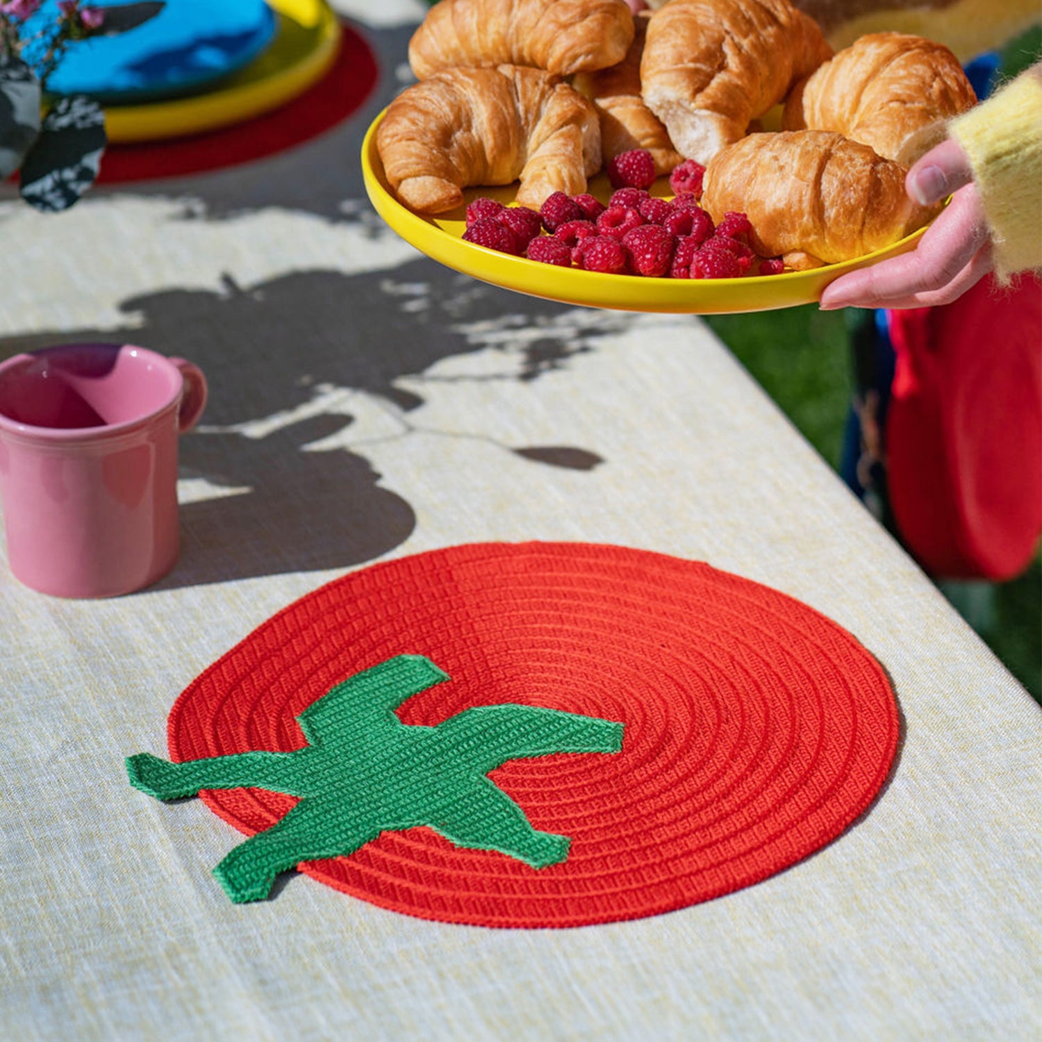 placemat in the shape of a red tomato with green stem